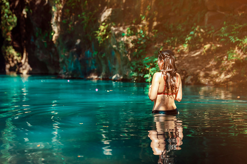 young Latina woman standing in blue green waters of Rio Blanco in Costa Rica. High quality photo