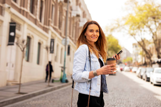 istock Happy woman using the phone while walking on the street 1421514991