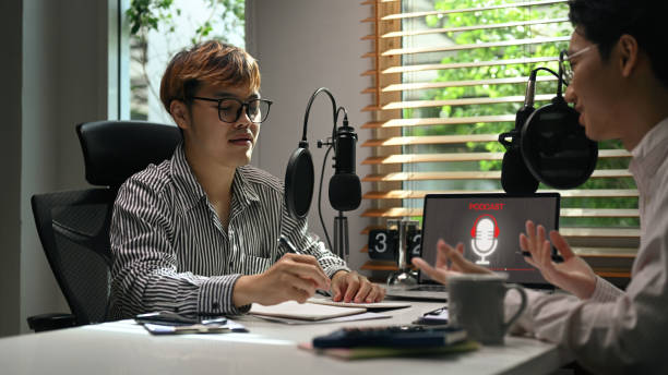 istock Young man radio host interviewing guest in studio while recording live podcast in studio. Radio, podcasts, blogging and technology concept. 1421518924