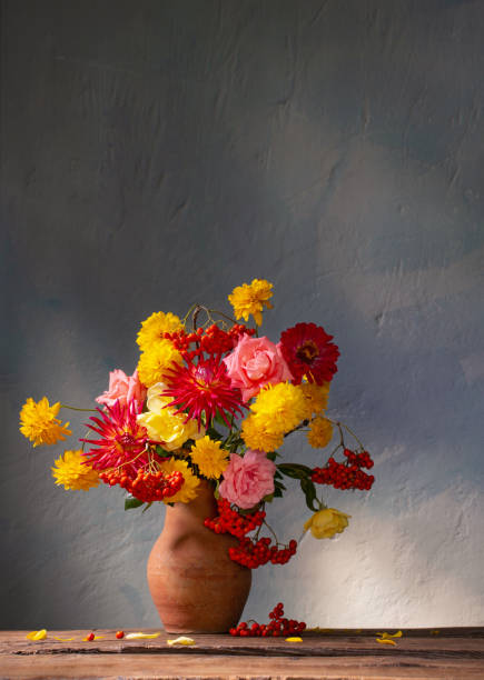 istock red and yellow flowers on jug in sunlight on background dark wall 1421519734