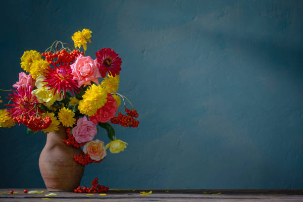 istock red and yellow flowers on jug in sunlight on background dark wall 1421519737