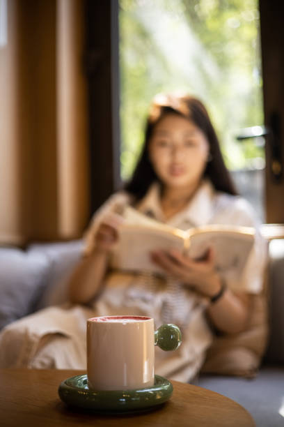 istock A cup of coffee on table with women reading a book background 1421520928