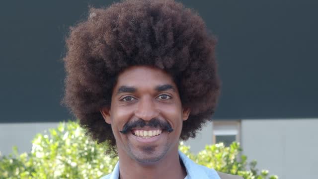 Portrait of smiling african american man with mustache and afro hair looking at camera. Millennial man, freelancer