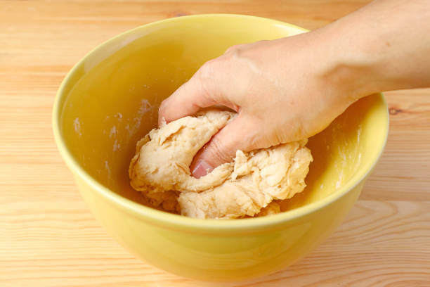 Hand kneading bread dough in a mixing bowl