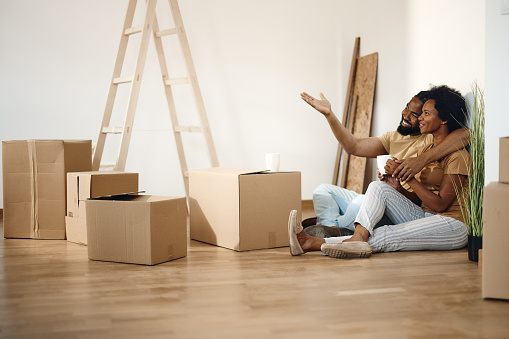 Happy African American couple making decoration plans while taking a break from unpacking their belongings in a new home. Copy space.