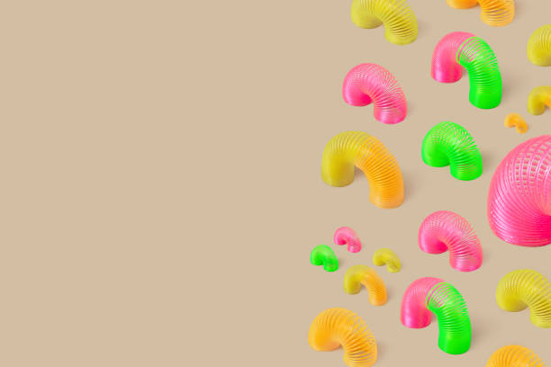 Rainbow plastic multicolored spiral toys or slinky on beige background. Minimalism. Creative seamless pattern
