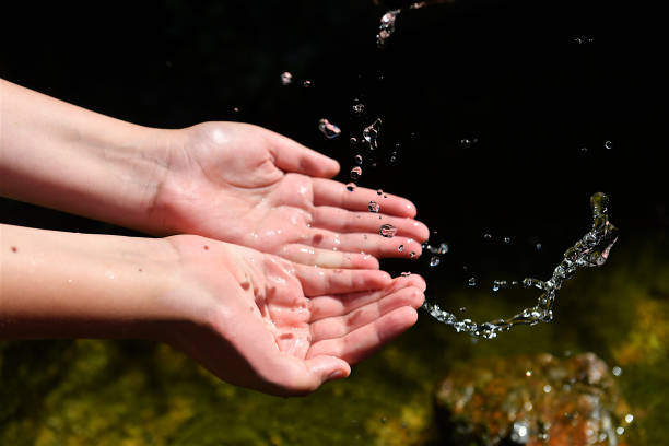 istock Drops of water falling into palms hands 1421533553