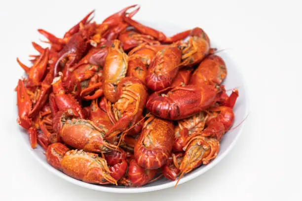 Photo of Red boiled crayfish with lemon on the plate isolated on a white background