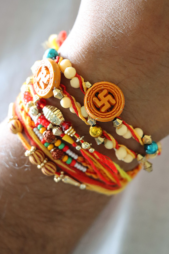 Stock photo showing close-up view of an Indian man's wrist on which he is wearing rakhi string bracelets after taking part in the Hindu festival of brotherhood and love, Raksha Bandhan ceremony. During this annual event, held on the last day of the Hindu lunar calendar month of Shraavana, sisters tie a rakhi, string bracelet, on their brothers' wrists to signify protection.