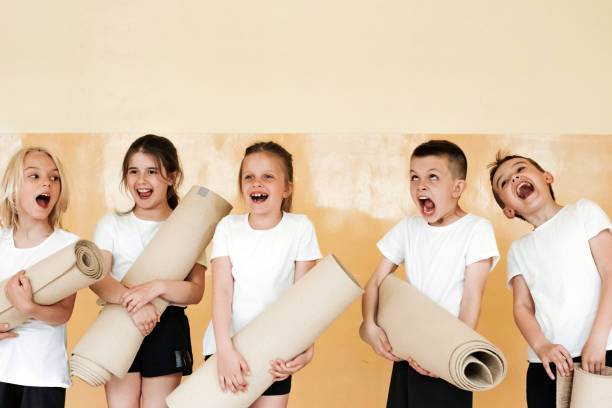 elementary schoolchildren holding yoga mats in gym stock photo