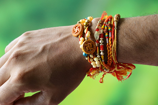 Stock photo showing close-up view of an Indian man's wrist on which he is wearing rakhi string bracelets after taking part in the Hindu festival of brotherhood and love, Raksha Bandhan ceremony. During this annual event, held on the last day of the Hindu lunar calendar month of Shraavana, sisters tie a rakhi, string bracelet, on their brothers' wrists to signify protection.