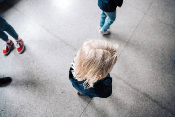 ovcerhead view on single little schoolboy isolated in the corridor high angle view on single elementary schoolboy standing isolated in the corridor school exclusion stock pictures, royalty-free photos & images