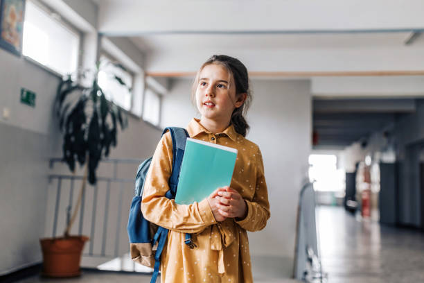 istock portraits of happy elementary schoolgirl holding workbook 1421536816