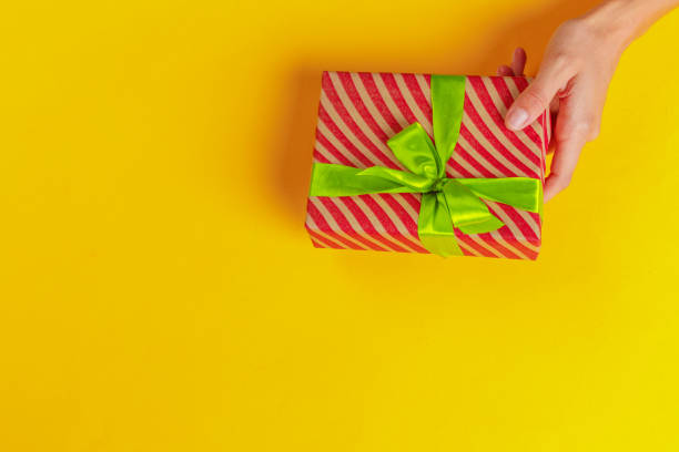 istock Woman holding gift box on color background 1421536914