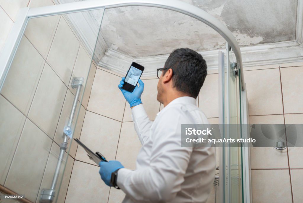 Man Examining Moldy White Wall Insurance Adjuster Taking Pictures By Smartphone Of Bathroom Ceiling Damage Fungal Mold Stock Photo
