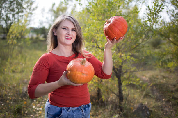 Portrait of beautiful middle-aged blonde woman with pumpkin ready for halloween celebration, mockup for postcard and invitation or advertisement stock photo