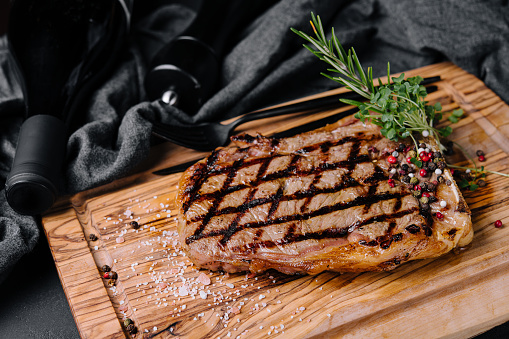Grilled striploin sliced steak on cutting board over stone table
