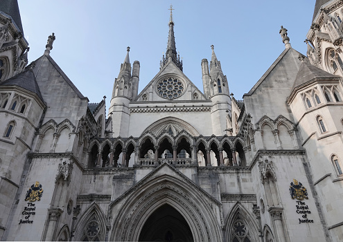 London,United Kingdom-26 March 2018:Some people crossing the road in front of the Palace of the Royal Courts of Justice