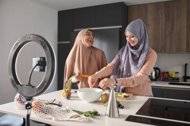 istock Two muslim food vloggers laughing while preparing a salad at kitchen. 1421547761