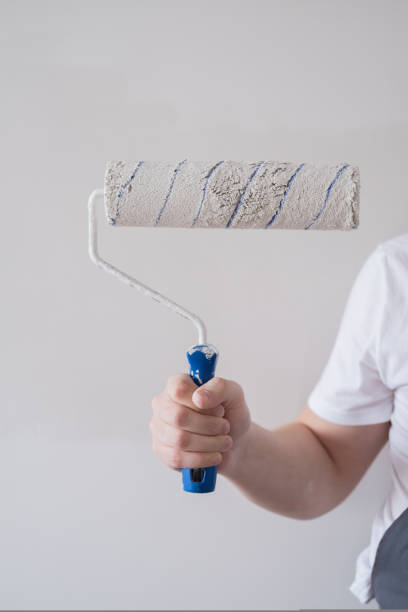 istock A man in overalls holds a wall paint roller in his hands 1421548529