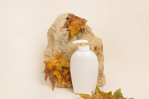istock Soap or lotion bottle, brick and dry autumn leaves on light background, creative still life cosmetic photography 1421551672
