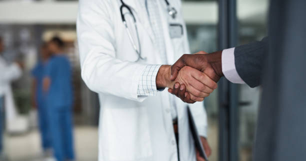 médecin serrant la main d’un homme d’affaires pour un accord d’entreprise, une réunion et un contrat de soins de santé. soutien à la poignée de main, collaboration et partenariat médical b2b pour une opportunité de réseautage et un accord de  - grelotter photos et images de collection