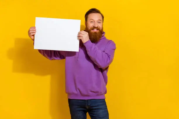 Photo of Portrait of cheerful person hands hold demonstrate empty space list proposition isolated on yellow color background