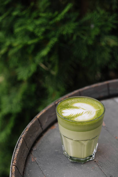 istock Matcha latte green milk foam cup on wood barrel 1421557028