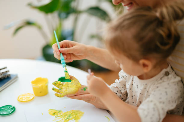 istock Anonymous Mother Painting on Daughter's Palm 1421557913