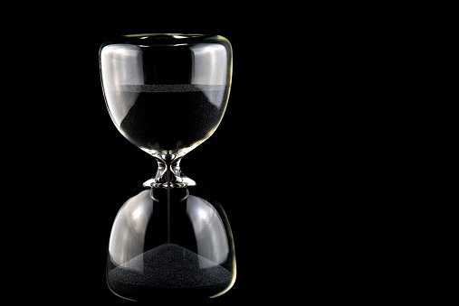Hourglass with black sand isolated on a black background