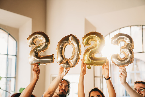 Close up shot of golden balloons with 2023 text to celebrate the New Year. Sunset time. Copy space.