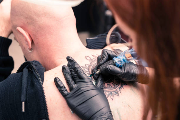 istock Female tattoo artist making a tattoo 1421560938