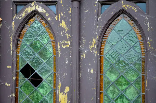 repair of stained glass with lead sealing between square or diamond-shaped glasses. green textured window of the door of the chapel or the tomb neo-gothic arch, sealing
