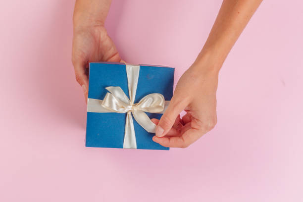 istock Woman holding gift box on color background 1421563222