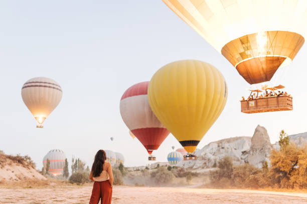 Young woman feels happy and smiling while looking at hot air balloons in Cappadocia stock photo