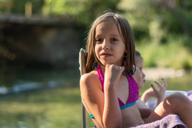istock Girls sitting by the river during summer day 1421564748