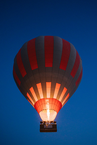 Hot air balloon with burning flame are flying over dark blue sky background