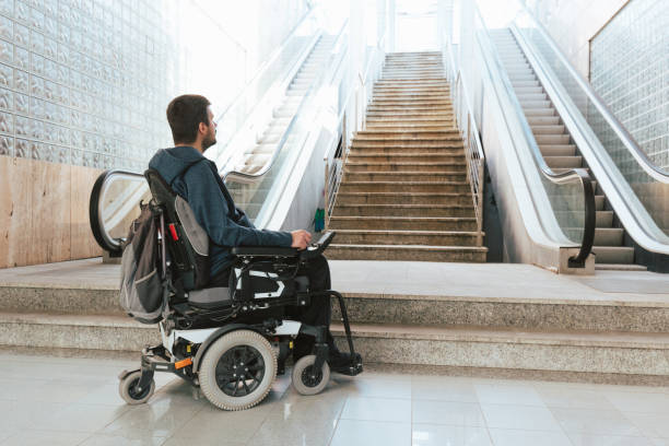 Man with disability on wheelchair stopped in front of staircase stock photo