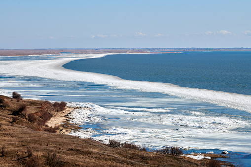 February seashore with melting ice near shore, seasonally nature landscape of coming spring. Russian Azov sea in Rostov on Don region, beautiful seaside weather changing