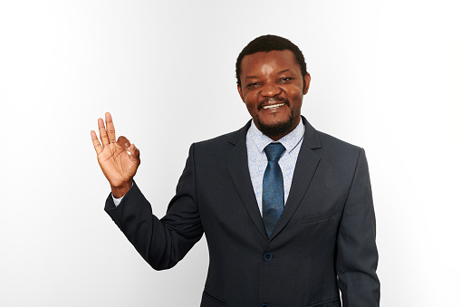 Smiling african american black man in business suit with OK gesture isolated on white background. Happy black businessman, chief executive officer approves good deal