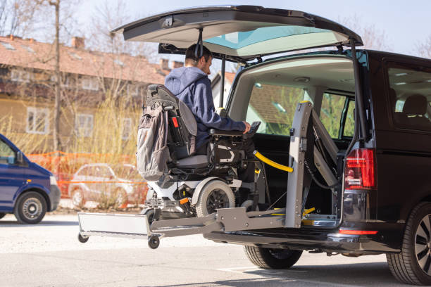 Man with disability using wheelchair lift to get in the van stock photo