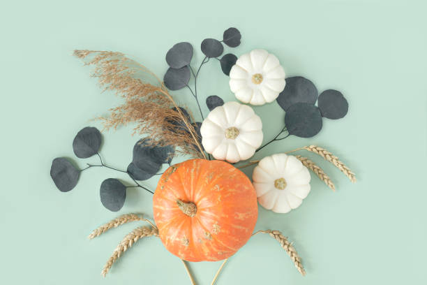 istock Autumn composition. Green desk with pumpkins and eucalyptus branch. Flat lay, top view, copy space. Nordic, hygge, cozy home concept. Thanksgiving fall decoration. Halloween Modern Invitation Mock up. 1421572769