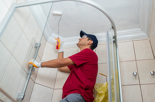 Male Worker Painting Bathroom Ceiling