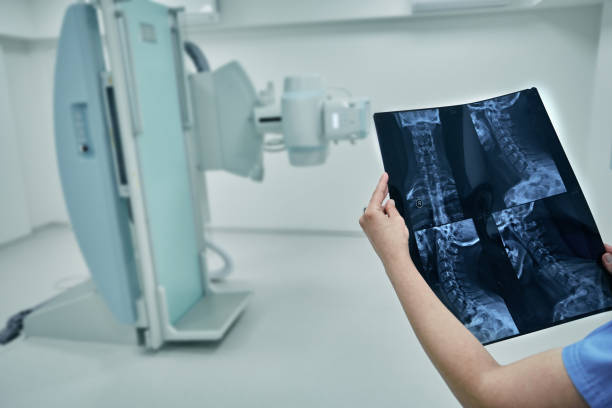 istock Radiologist looking at and analyzing X-ray of patient's cervical spine against background of modern radiology room at hospital 1421579352