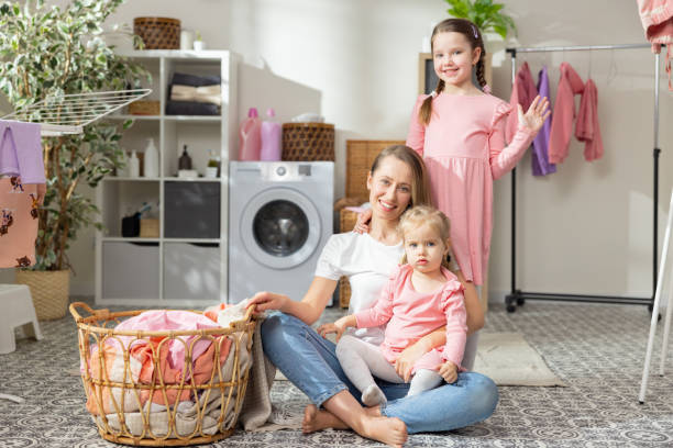 istock A busy mom with two daughters spends time in the laundry room while doing household chores. Woman sorting clothes smiles at camera along with her children 1421579530