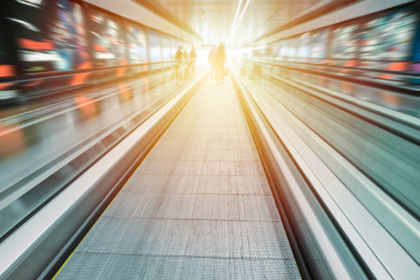 Moving sidewalk in airport terminal Motion blur image of incidental people and airport terminal. airport travelator stock pictures, royalty-free photos & images