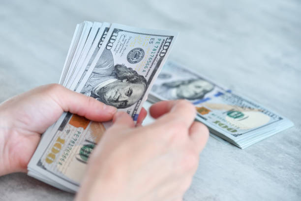 istock Woman hands counting dollars on table 1421580248