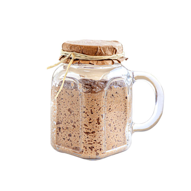Active sourdough starter in glass jar. Rye leaven for bread isolated on white background. Traditional bread baking concept.