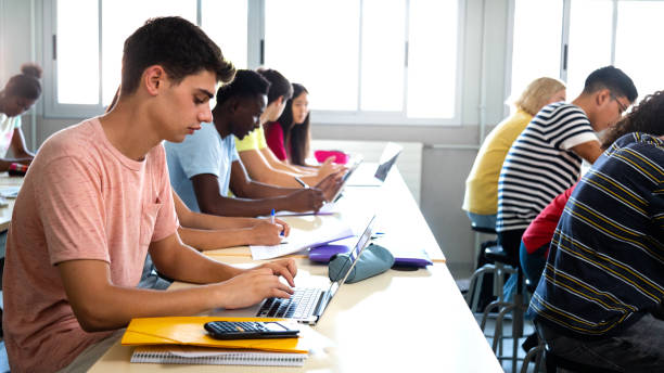 istock Side view of group of multiracial high school students studying and using laptops in class. 1421586023