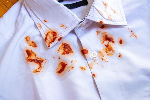 Food stains on shirt. Top view tomato sauce dirt on white shirt.